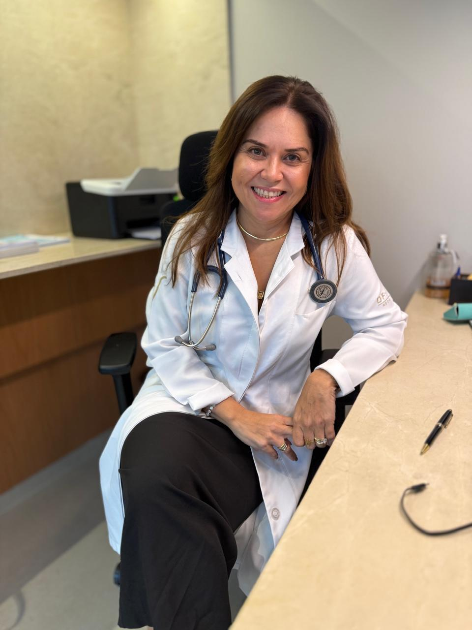 Dra. Hélia Beatriz sentada em seu consultório